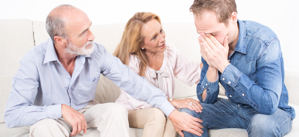 How to Tell Your Family You Need Help with Alcohol Emerald Isle Health and Recovery - A middle-aged man is speaking with his parents on the couch and explaining to them that he is struggling with an alcohol addiction and is ready to seek professional help at an alcohol rehab.